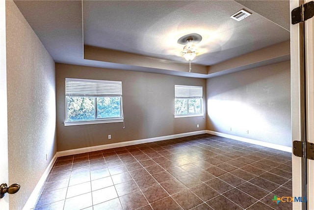 243 Arendes Dr, New Braunfels, TX 78132 - unfurnished room featuring a tray ceiling, baseboards, dark tile patterned flooring, a textured ceiling, and a textured wall