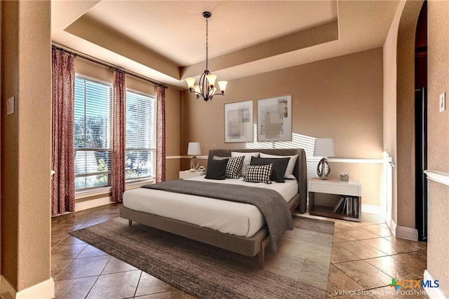 243 Arendes Dr, New Braunfels, TX 78132 - bedroom with tile patterned floors, multiple windows, arched walkways, a tray ceiling, and a textured wall
