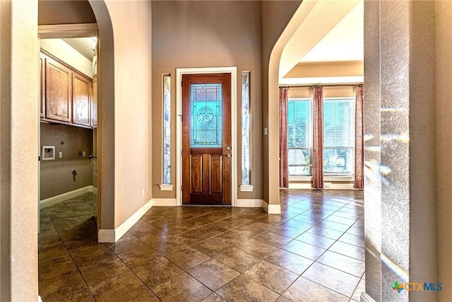 243 Arendes Dr, New Braunfels, TX 78132 - foyer entrance with plenty of natural light, arched walkways, baseboards, and dark tile patterned floors