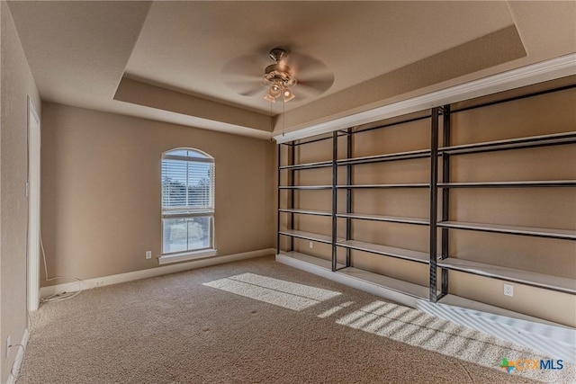 carpeted empty room with a tray ceiling and ceiling fan