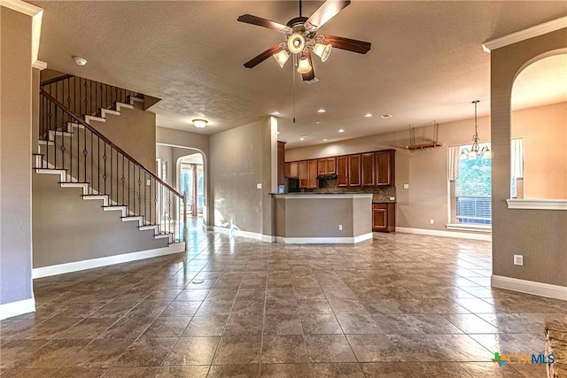 243 Arendes Dr, New Braunfels, TX 78132 - unfurnished living room featuring arched walkways, healthy amount of natural light, baseboards, and a textured ceiling