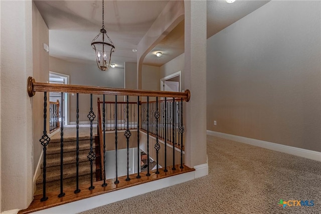 stairway featuring carpet flooring and a notable chandelier