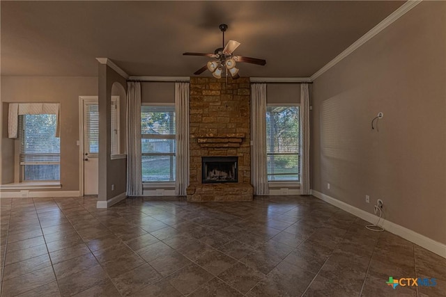 unfurnished living room with a stone fireplace, a wealth of natural light, crown molding, and ceiling fan