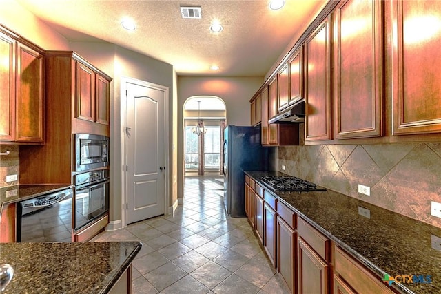 243 Arendes Dr, New Braunfels, TX 78132 - kitchen with black appliances, under cabinet range hood, a textured ceiling, dark stone counters, and backsplash