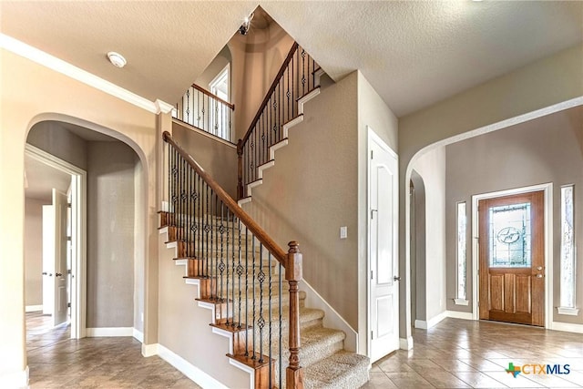 243 Arendes Dr, New Braunfels, TX 78132 - tiled entryway featuring stairs, arched walkways, a textured ceiling, and baseboards