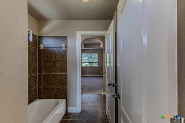 bathroom featuring tile patterned floors, a textured ceiling, and tiled shower / bath