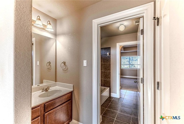 243 Arendes Dr, New Braunfels, TX 78132 - bathroom featuring vanity, a bathtub, tile patterned floors, a textured wall, and baseboards
