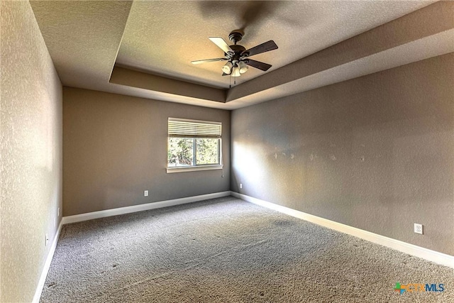 243 Arendes Dr, New Braunfels, TX 78132 - empty room with carpet, ceiling fan, baseboards, a textured ceiling, and a tray ceiling