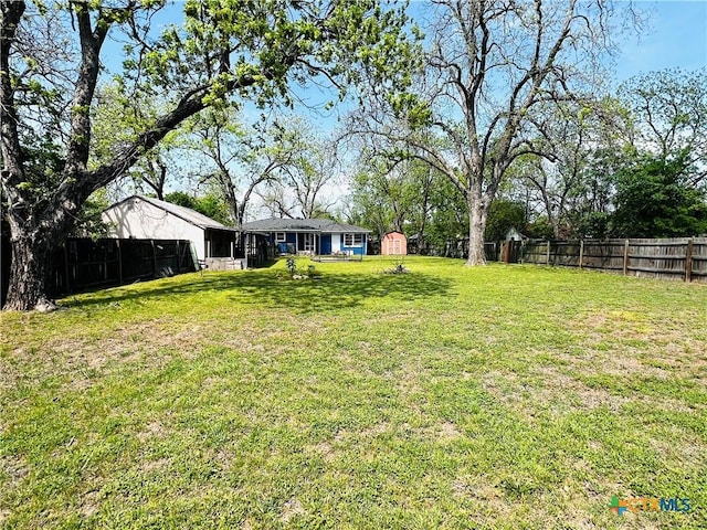 view of yard with a fenced backyard, an outbuilding, and a storage shed