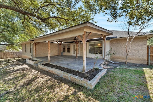 rear view of house with french doors, a patio, brick siding, and fence