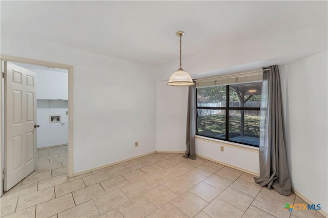 spare room featuring light tile patterned floors and baseboards