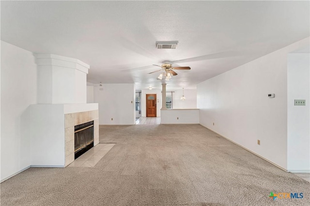 unfurnished living room featuring light colored carpet, a fireplace, visible vents, and a ceiling fan