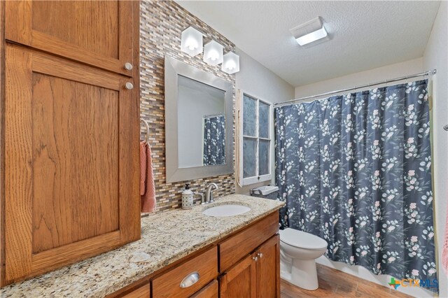 bathroom with vanity, a textured ceiling, decorative backsplash, hardwood / wood-style flooring, and toilet