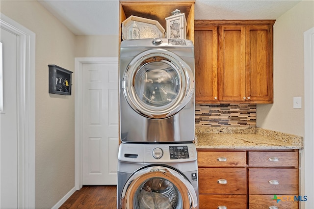 washroom featuring cabinets, dark hardwood / wood-style floors, and stacked washer / dryer