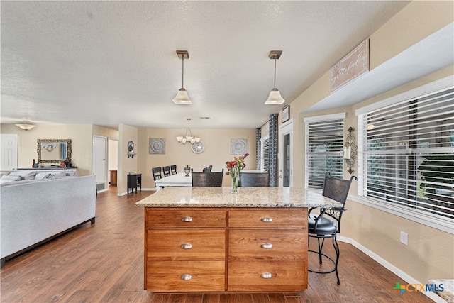 kitchen featuring pendant lighting, a kitchen breakfast bar, dark hardwood / wood-style floors, and a kitchen island