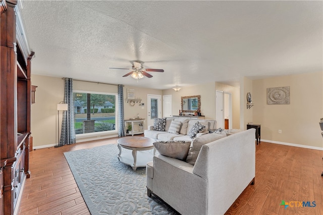 living room featuring a textured ceiling, light wood-type flooring, and ceiling fan