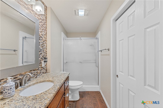 bathroom with hardwood / wood-style floors, vanity, an enclosed shower, toilet, and decorative backsplash