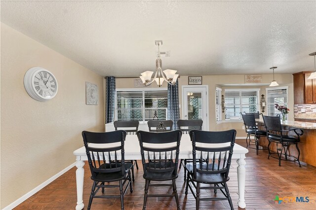 dining space featuring dark hardwood / wood-style floors, a textured ceiling, and a chandelier