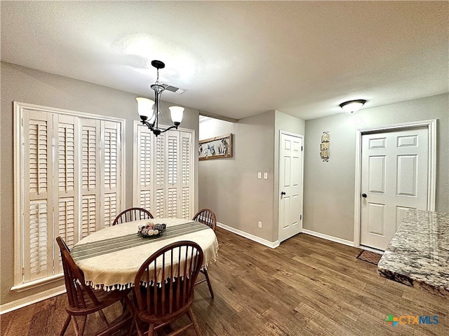 dining space with dark hardwood / wood-style flooring, a notable chandelier, and a textured ceiling