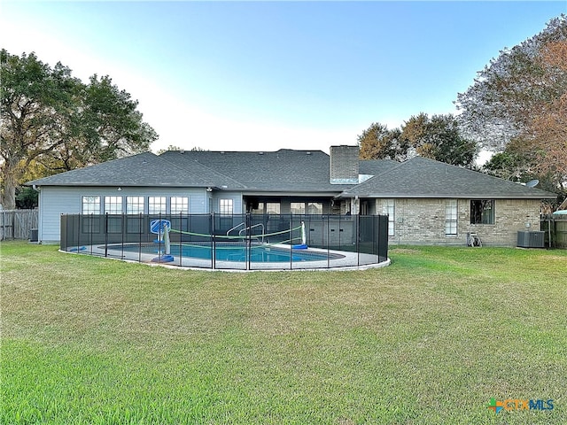 exterior space with central AC unit, a fenced in pool, and a yard