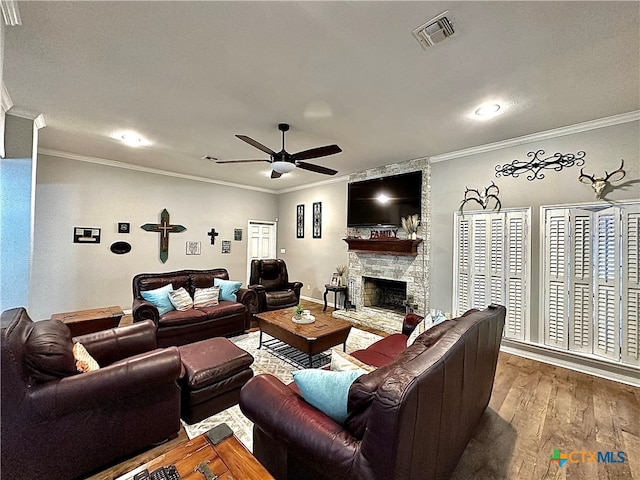 living room with a fireplace, wood-type flooring, ceiling fan, and crown molding