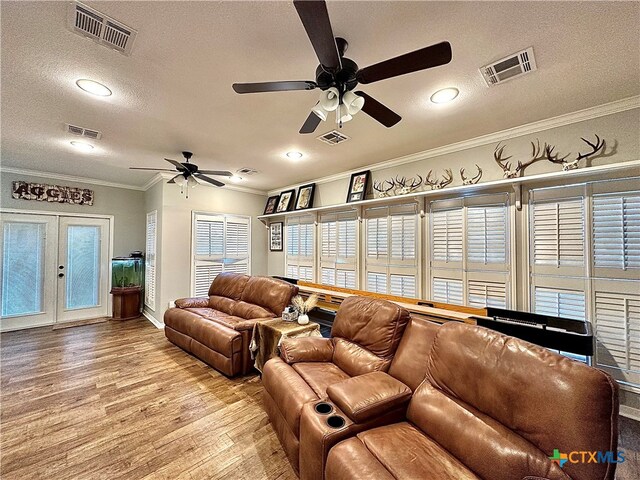 living room featuring ceiling fan, a textured ceiling, light wood-type flooring, and ornamental molding