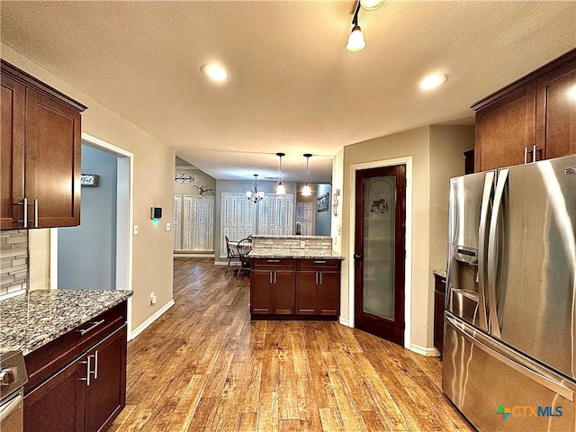 kitchen with tasteful backsplash, stainless steel fridge, light wood-type flooring, hanging light fixtures, and an inviting chandelier