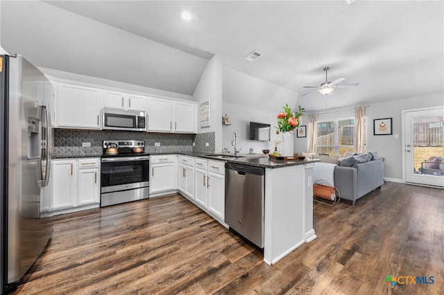 kitchen featuring stainless steel appliances, white cabinetry, kitchen peninsula, lofted ceiling, and dark hardwood / wood-style flooring