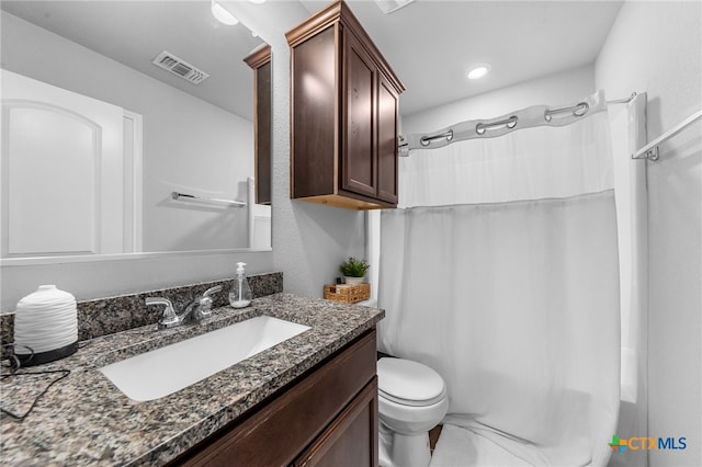 bathroom with walk in shower, vanity, and toilet