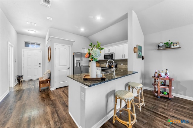 kitchen featuring stainless steel appliances, lofted ceiling, dark hardwood / wood-style flooring, kitchen peninsula, and white cabinetry