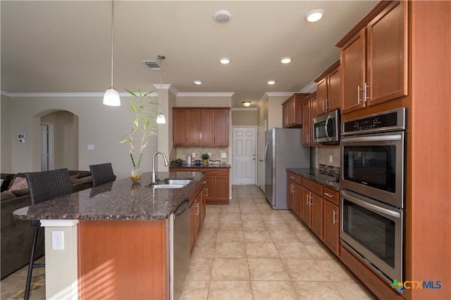 kitchen featuring sink, dark stone countertops, appliances with stainless steel finishes, a kitchen breakfast bar, and decorative backsplash