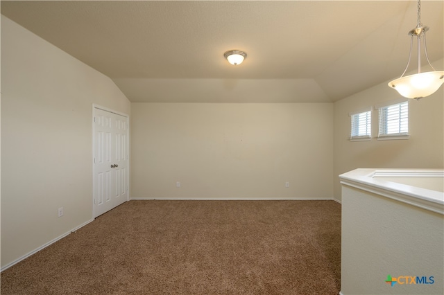 carpeted spare room featuring vaulted ceiling