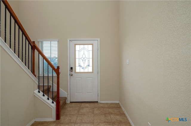 entryway with light tile patterned floors and a high ceiling