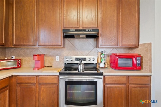 212 Nairm Ln, Temple, TX 76502 - kitchen featuring stainless steel range with electric cooktop, under cabinet range hood, light countertops, decorative backsplash, and brown cabinets