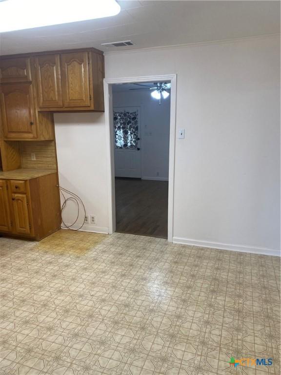 interior space with light floors, baseboards, visible vents, and crown molding