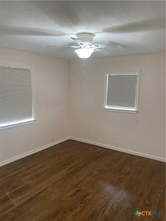 unfurnished room featuring a ceiling fan, a textured ceiling, baseboards, and dark wood-type flooring