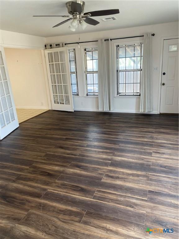 interior space featuring a ceiling fan, visible vents, baseboards, and wood finished floors