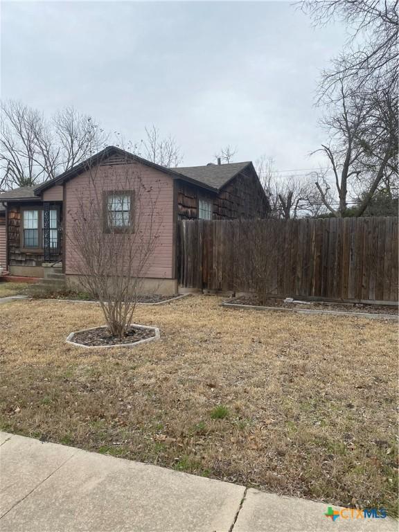 view of side of home featuring a yard and fence