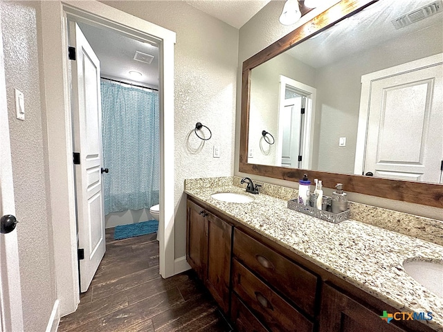 bathroom with toilet, vanity, hardwood / wood-style floors, and curtained shower