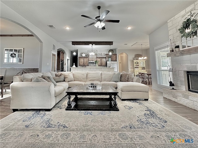 living room with hardwood / wood-style floors, ceiling fan with notable chandelier, and a fireplace