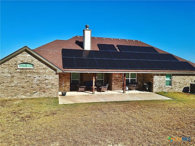 rear view of property with a yard, solar panels, and a patio