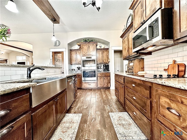 kitchen featuring stainless steel appliances, backsplash, a textured ceiling, dark hardwood / wood-style floors, and pendant lighting