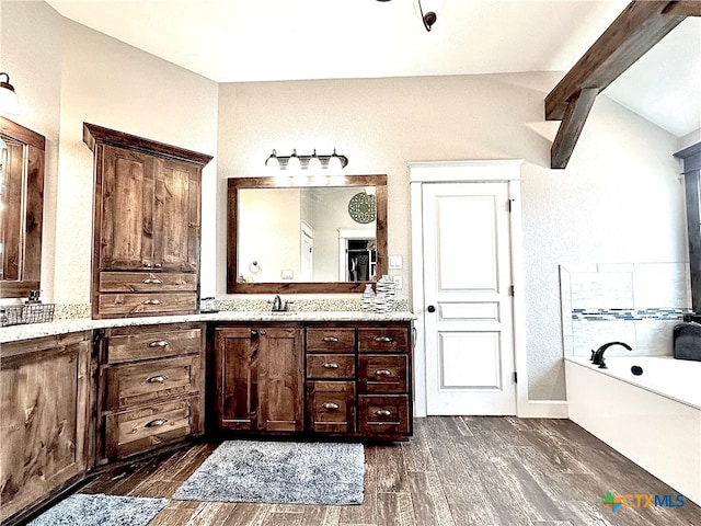 bathroom with hardwood / wood-style floors, vanity, a bathtub, and lofted ceiling