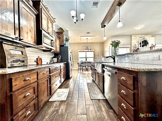 kitchen featuring stainless steel appliances, dark hardwood / wood-style flooring, an inviting chandelier, sink, and pendant lighting