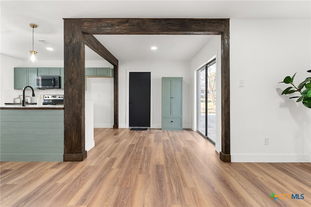 interior space with sink, beam ceiling, and light hardwood / wood-style flooring