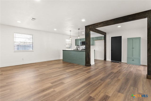 unfurnished living room featuring sink, hardwood / wood-style floors, and beamed ceiling