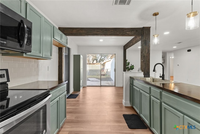 kitchen featuring sink, green cabinets, decorative light fixtures, stainless steel range with electric stovetop, and beam ceiling