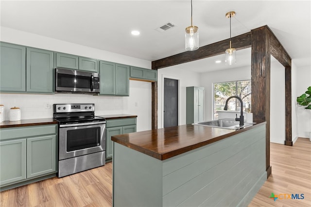 kitchen with stainless steel appliances, hanging light fixtures, wood counters, green cabinets, and sink