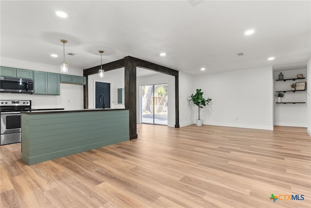 kitchen with appliances with stainless steel finishes, hanging light fixtures, light hardwood / wood-style floors, and sink