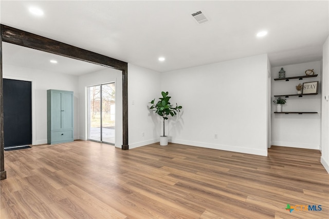 unfurnished room with light wood-type flooring and beamed ceiling